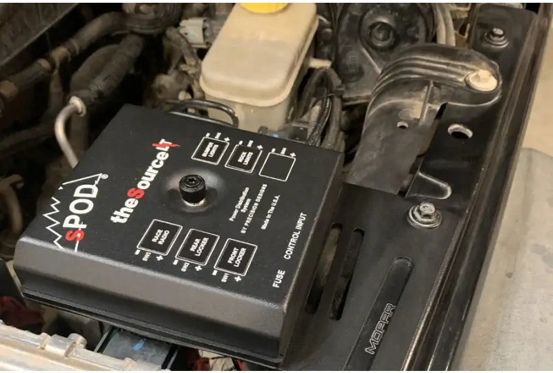 SPOD SourceLT control system installed under a car hood, featuring a 6-circuit control panel for 12VDC accessories in a Jeep JK 2009+